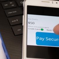 Pay secure online concept of cellphone on latop keyboard with different payment options to choose from with persons finger about to make a transaction