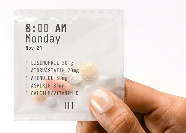 Illustrative labeled daily medication pack held in a hand